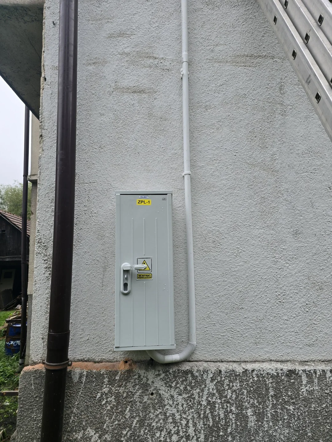 Skrzynka elektryczna i trasa przewodów na elewacji — Kalwaria Zebrzydowska.